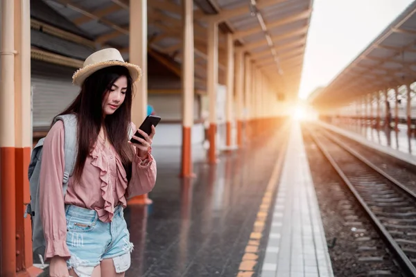 Smiling woman traveler with backpack holding smartphone on holid — Stock Photo, Image