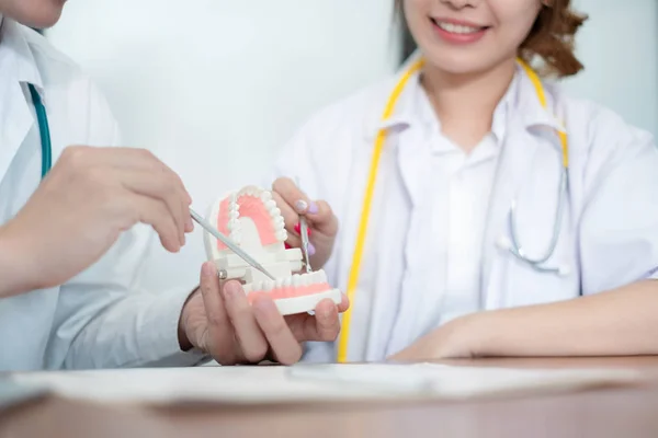 Врач-стоматолог в белой униформе держит зуб модели и зубной t — стоковое фото
