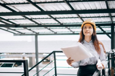 helmat giyen genç mühendisler plan modunu tutarak yukarı bakıyor