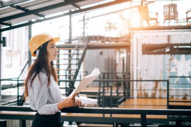 helmat giyen genç mühendisler plan modunu tutarak yukarı bakıyor