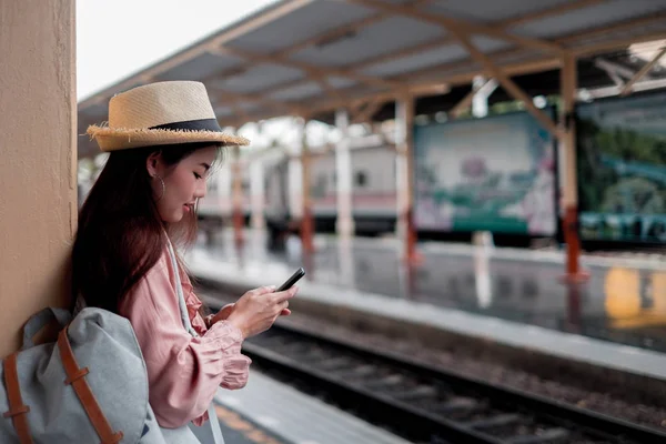 Mujer sonriente viajero con mochila sosteniendo smartphone en holid — Foto de Stock