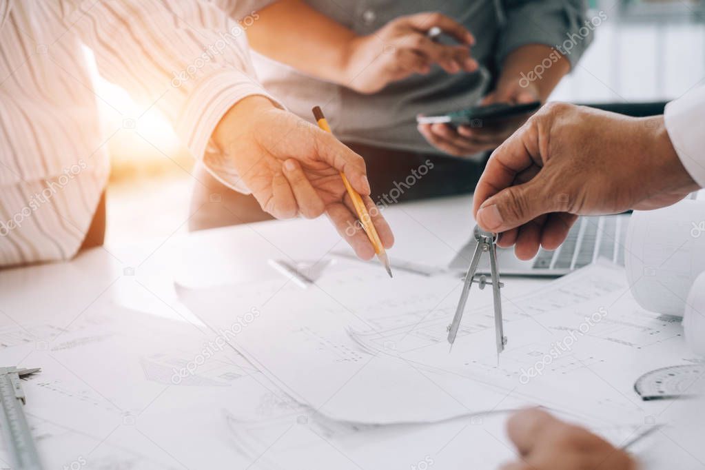 engineers pointing to building on blueprint to drawing design bu