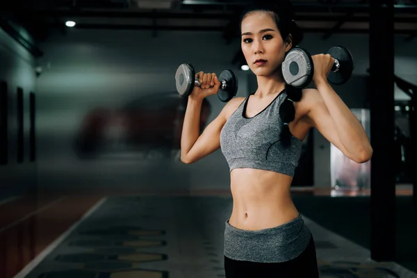 Deporte mujer en gimnasio gimnasio club haciendo ejercicio para los brazos con dum — Foto de Stock