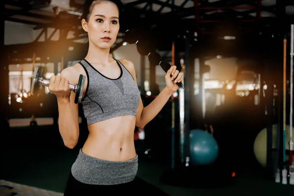 Deporte mujer en gimnasio gimnasio club haciendo ejercicio para los brazos con dum — Foto de Stock