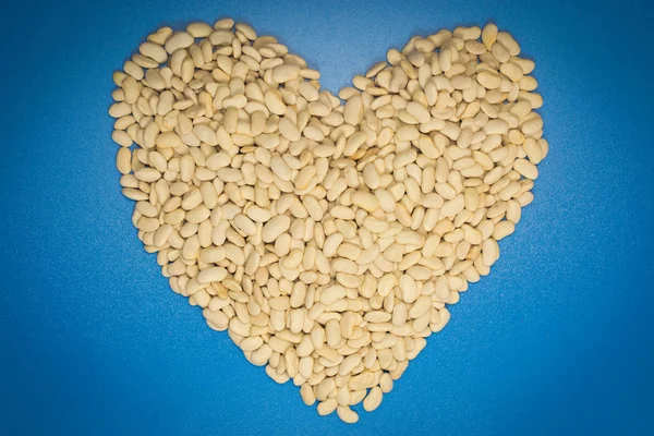 Mavi arka planda kalp şeklinde beyaz fasulyeler.