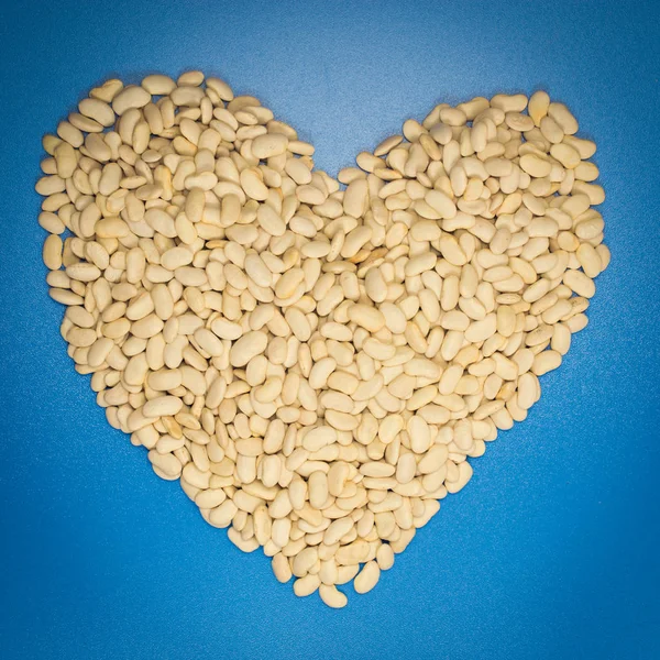 Mavi arka planda kalp şeklinde beyaz fasulyeler.