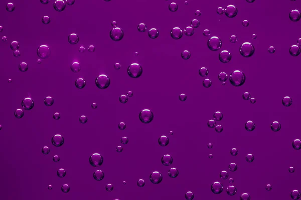 Mor arka plan üzerinde bir sıvı içinde hava kabarcıkları. Doku.