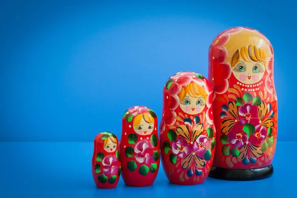 old wooden Russian nesting dolls on a blue background, a symbol of Russia, red, with copy space for text