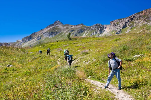 hiker with backpack climbing to the mountain with a group, hike