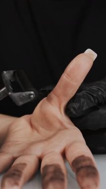 Bir adli tıp uzmanı parmak izi almak için bir kadının elini mürekkep silindiriyle sarıyor. Bir kadının elinin biyometriği. Dikey video.