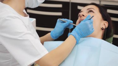 Dişçide genç bir kadın. Modern bir diş kliniğinde genç bir kadının dişlerini tedavi eden dişçilerin yakın çekimi. Kadın dişlerinin tedavisi.