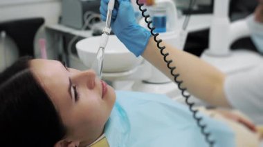 Dişçide genç bir kadın. Modern bir diş kliniğinde genç bir kadının dişlerini tedavi eden dişçilerin yakın çekimi. Kadın dişlerinin tedavisi.