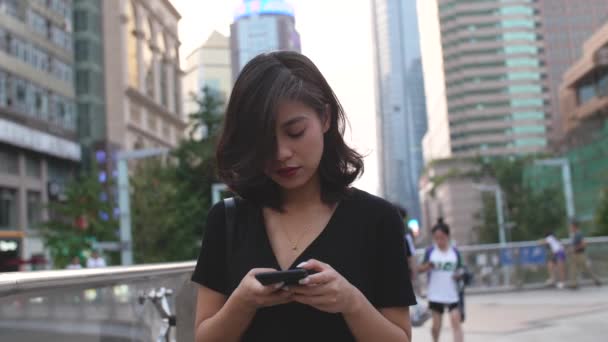 Jolie fille asiatique en utilisant le téléphone mobile dans la ville — Video