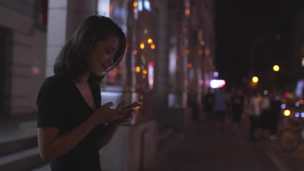 Giovane ragazza asiatica guardando telefono a piedi, 4k — Video Stock