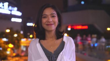 Şehirde kameraya bir güzel genç Asyalı kadın gülümseme