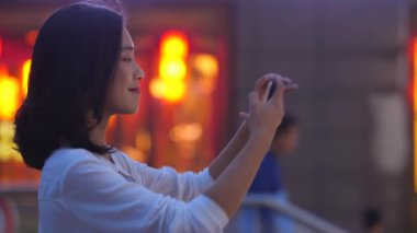 Şehirde cep telefonuyla fotoğraf çeken kadın