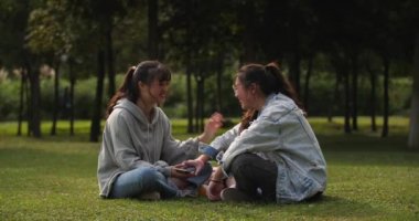 İki Asyalı kız çim ve mutlu konuşma oturuyor