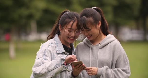 Dos asiático colegio chica usando móvil teléfono en campus — Vídeo de stock