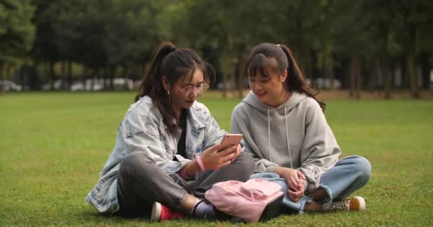 Две азиатки из колледжа используют мобильный телефон, чтобы сделать селфи в кампусе — стоковое видео