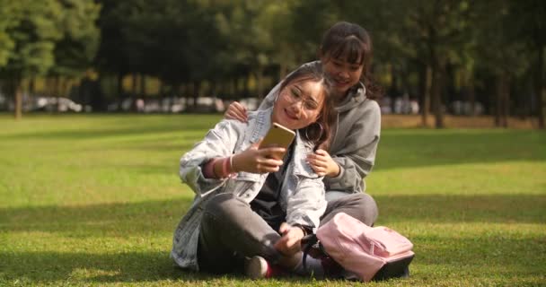 Dois asiático faculdade menina usando celular tomando selfie no campus — Vídeo de Stock