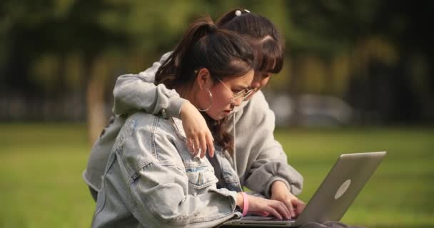 Kampüste dizüstü bilgisayar kullanan iki Asyalı üniversiteli kız — Stok video