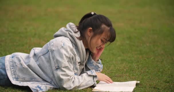 Högskolestudent läsebok på gräsmattan — Stockvideo