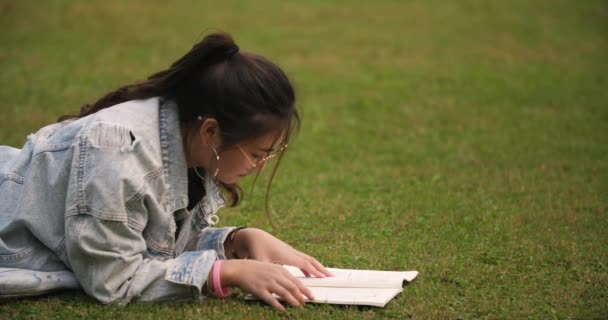 Estudiante universitario leyendo libro en el césped — Vídeos de Stock