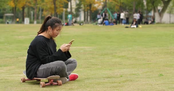 Asiática chica universitaria utilizando el teléfono móvil en el césped en el campus — Vídeo de stock