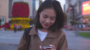 gece şehir caddesinde cep telefonu kullanarak güzel genç asyalı kadın, 4k
