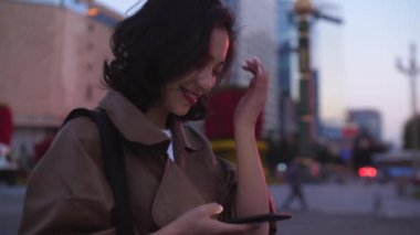 gece şehir caddesinde cep telefonu kullanarak güzel genç asyalı kadın, 4k
