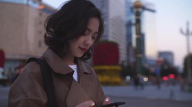 gece şehir caddesinde cep telefonu kullanarak güzel genç asyalı kadın, 4k