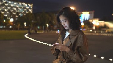 gece şehir caddesinde cep telefonu kullanarak güzel genç asyalı kadın, 4k