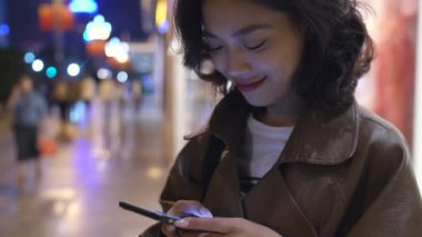 gece şehir caddesinde cep telefonu kullanarak güzel genç asyalı kadın, 4k