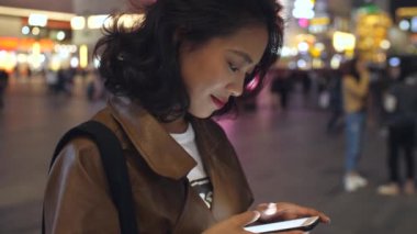 gece şehir caddesinde cep telefonu kullanarak güzel genç asyalı kadın, 4k
