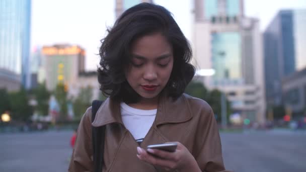 Симпатичная молодая женщина, пользующаяся мобильным телефоном на улице города ночью, 4к — стоковое видео
