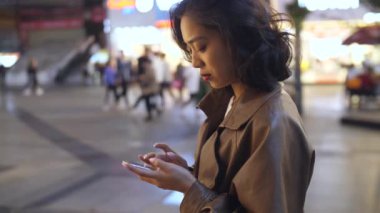 gece şehir caddesinde cep telefonu kullanarak güzel genç asyalı kadın, 4k