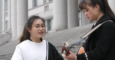 çinli kız öğrenciler gitar çalmak ve kampüste birlikte şarkı