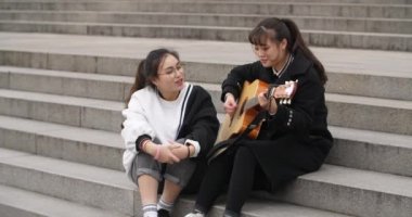 genç öğrenci onu şarkı arkadaşı için bir gitar eşliğinde oynamak