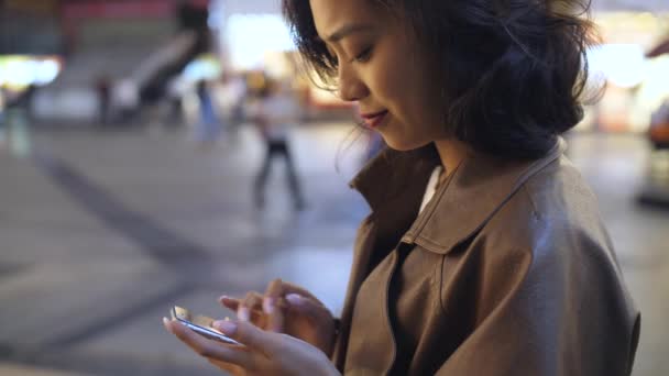 Bastante joven asiático mujer usando móvil en la ciudad calle en la noche, 4k — Vídeos de Stock