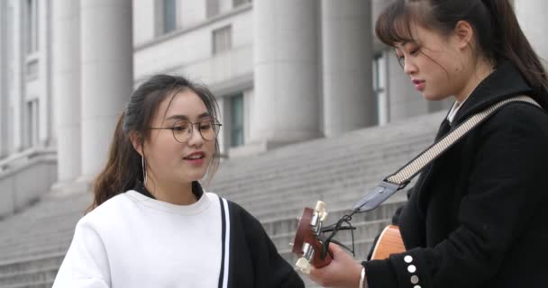 Chinesische Studentinnen spielen Gitarre und singen gemeinsam auf dem Campus — Stockvideo