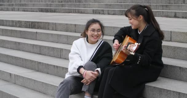 Две девушки исполняют песню под гитарным аккомпанементом — стоковое видео