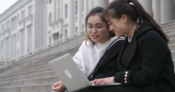 Две азиатские девушки с ноутбука и говорить с улыбкой счастливо в школе — стоковое видео