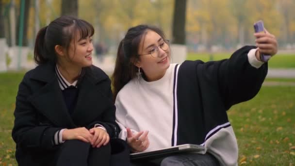 Две счастливые девушки используют мобильный телефон вместе — стоковое видео