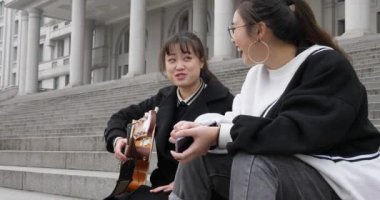 iki genç kız bir gitar ile adımlar üzerinde mutlu birlikte şarkı