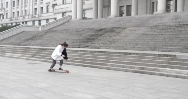 Linda menina chinesa jogando com uma placa de retorno fora de um edifício — Vídeo de Stock