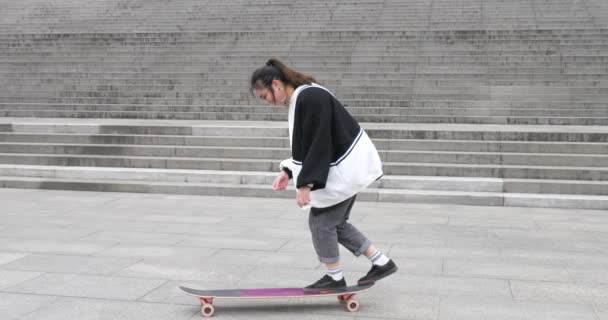 Милий китайський студент, що практикує скейтборд на кампусі — стокове відео