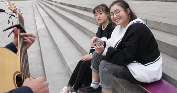 Dos asiático niñas cantando juntos en la escalinata con un guitarra chico sonriendo — Vídeos de Stock