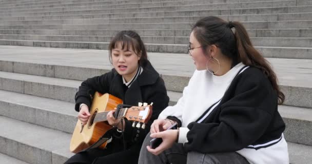 楽しみで歌う2人の若い女の子のためのギターの伴奏 — ストック動画