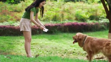 Asyalı kadın sahibi Golden Retriever suyunu besliyor..