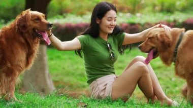 Uzun saçlı, yaz parkında iki köpeği olan Asyalı bir kadın.